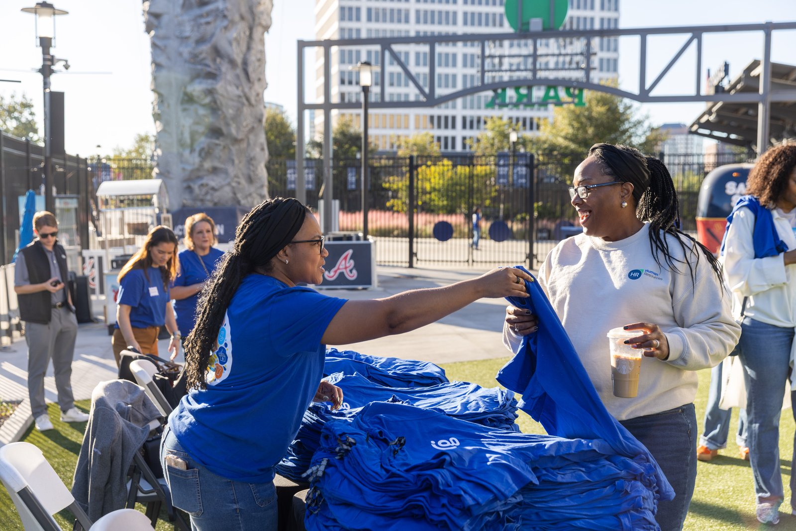 A volunteer in a blue Day of Service shirt hands out shirts near Truist Park.