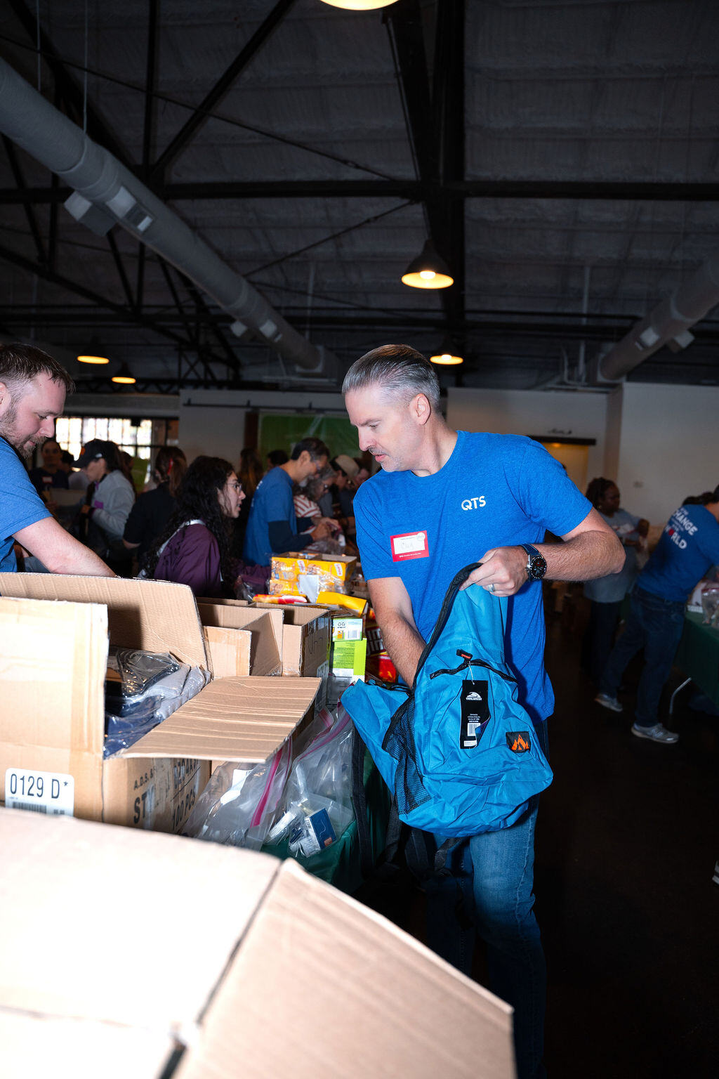 A volunteer fills a backpack from a table of supplies.