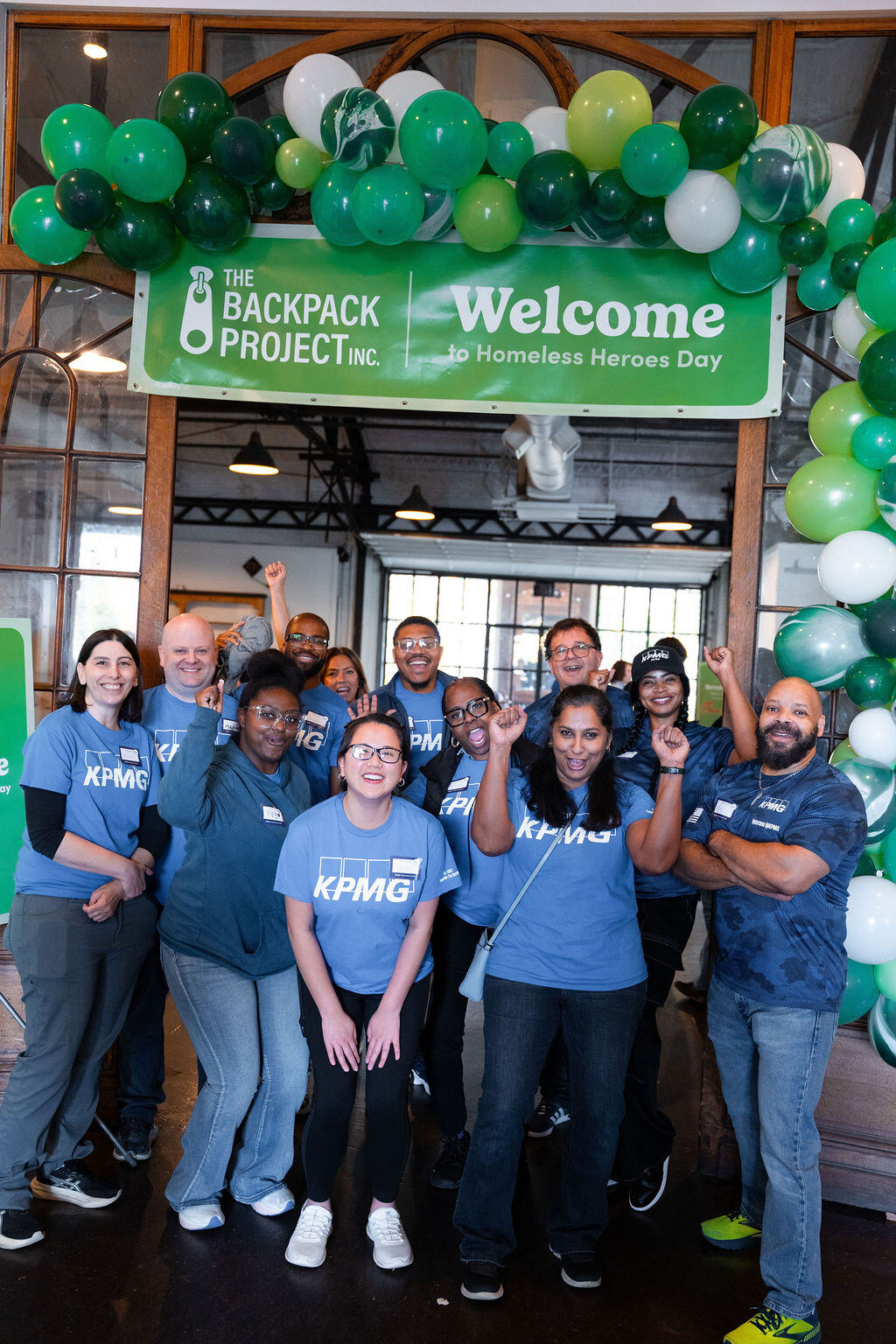 A company volunteer team gathers under the welcome balloon arch.