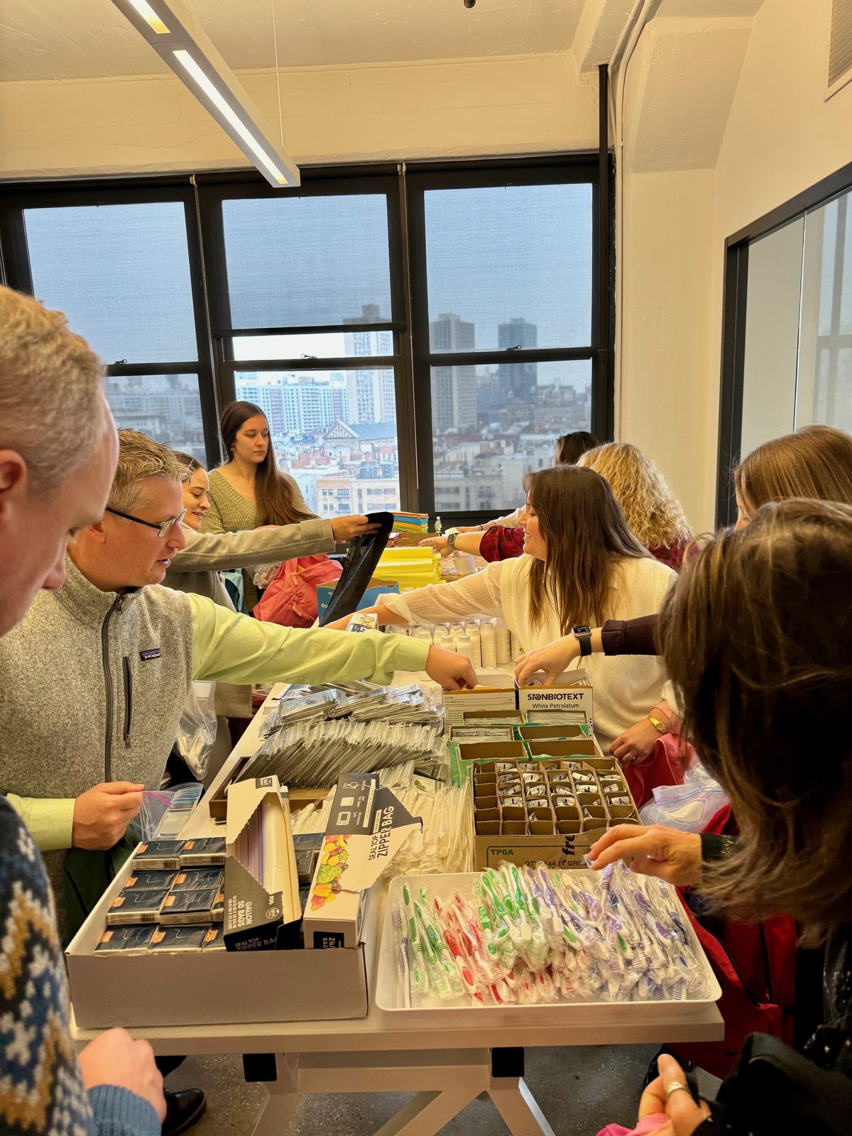 Volunteers pack backpacks and hygiene kits at a corporate packing event.